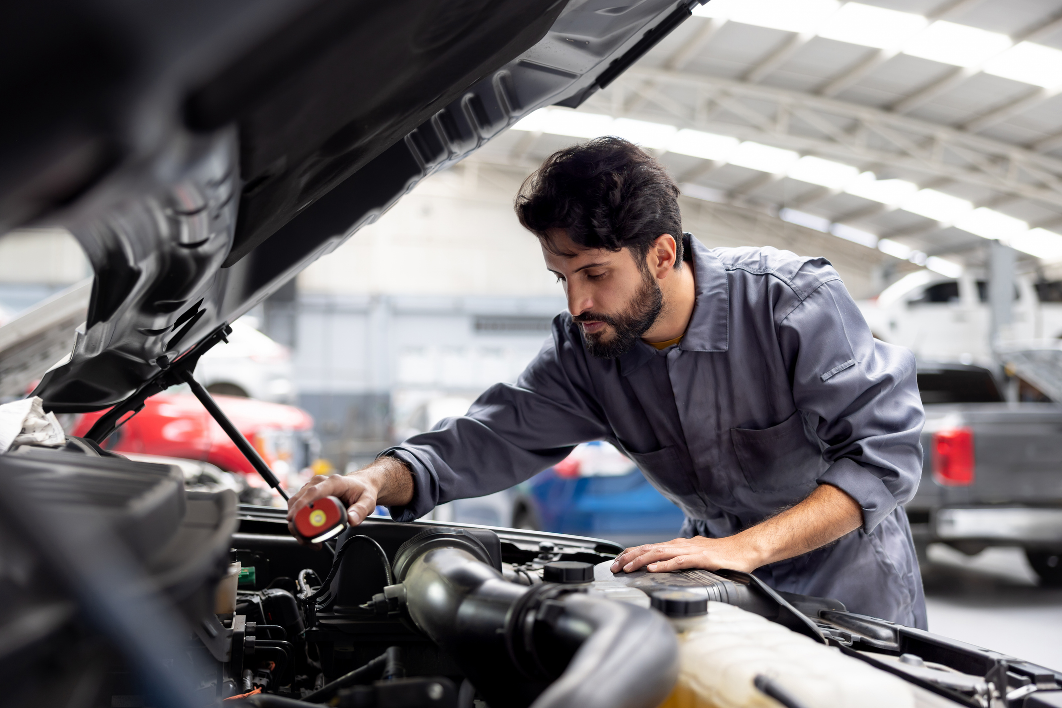 Mechanic working on a car in a garage, holding an object in his hand