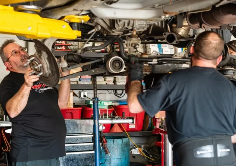 Mechanics servicing vehicle suspension